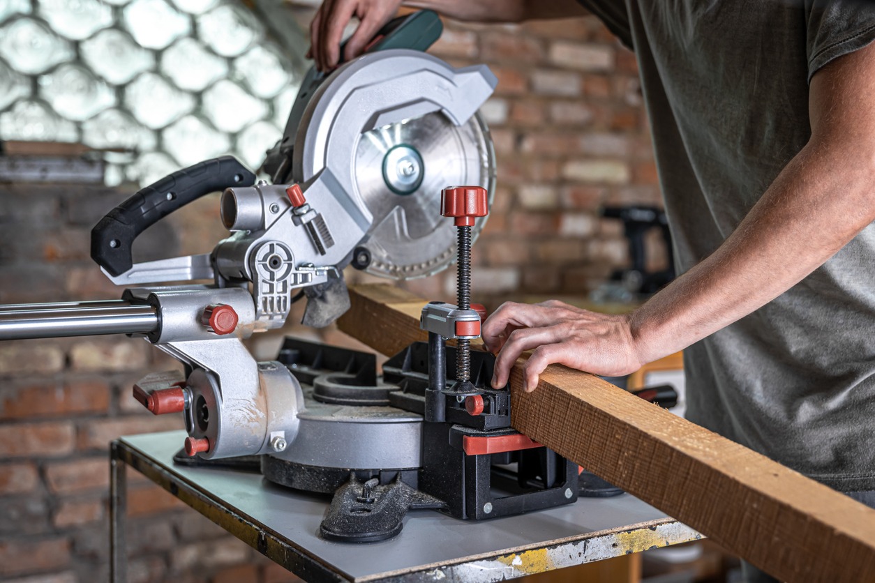 Man using a miter saw to cut a wooden plank
