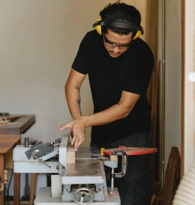 man using a jointer in a workshop