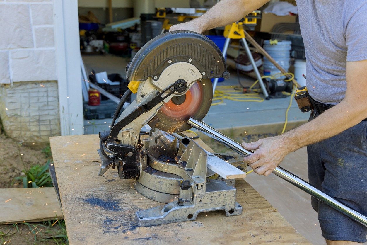 worker using a miter saw to cut a metal rod