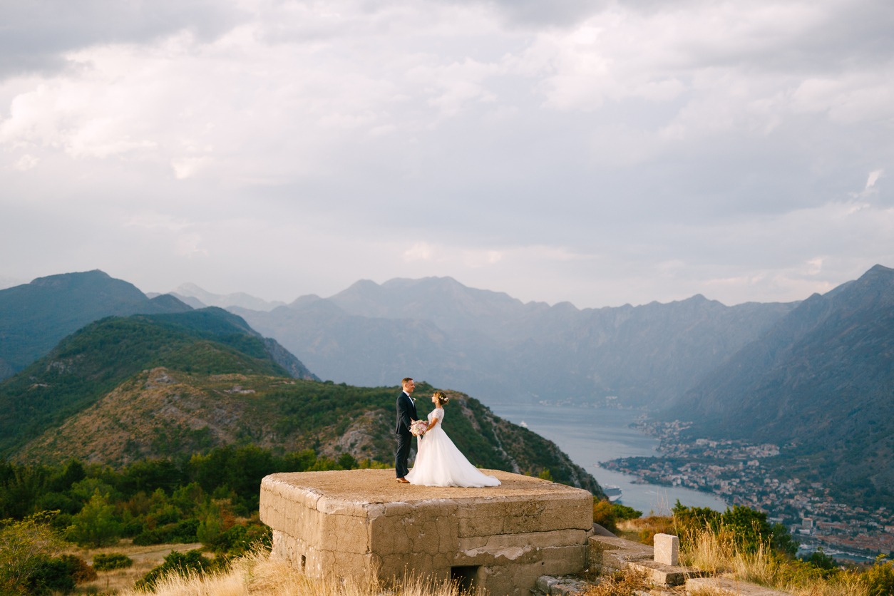 A drone captures an image of a bride and groom on top of a hill.