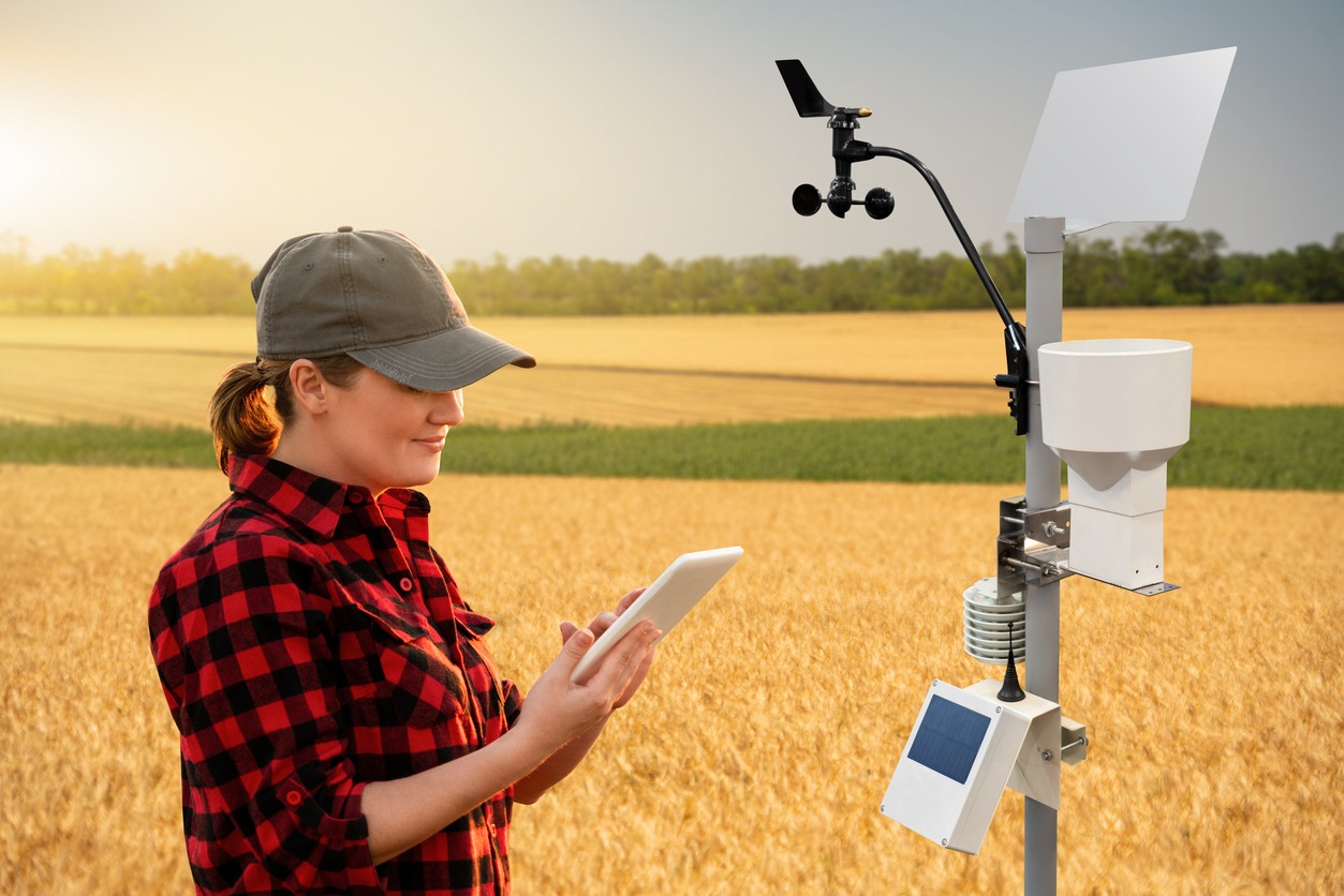 A farmer standing in a field next to a weather station