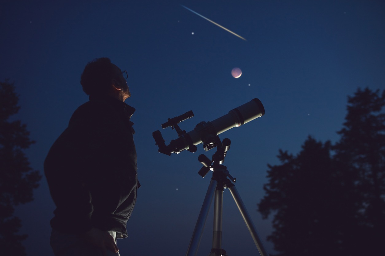 A man standing with a telescope to view the stars