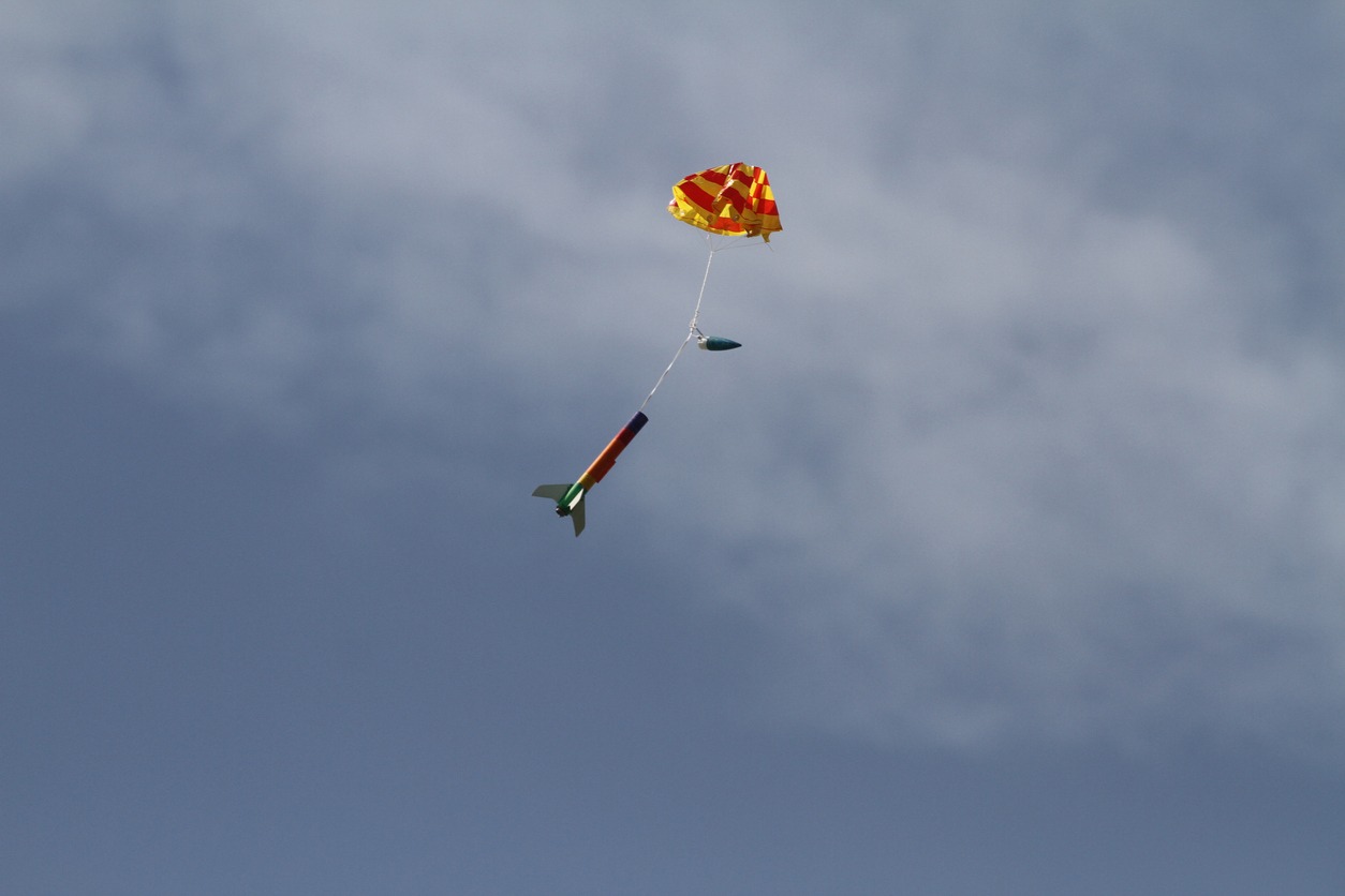 A model rocket attached to a parachute in the air