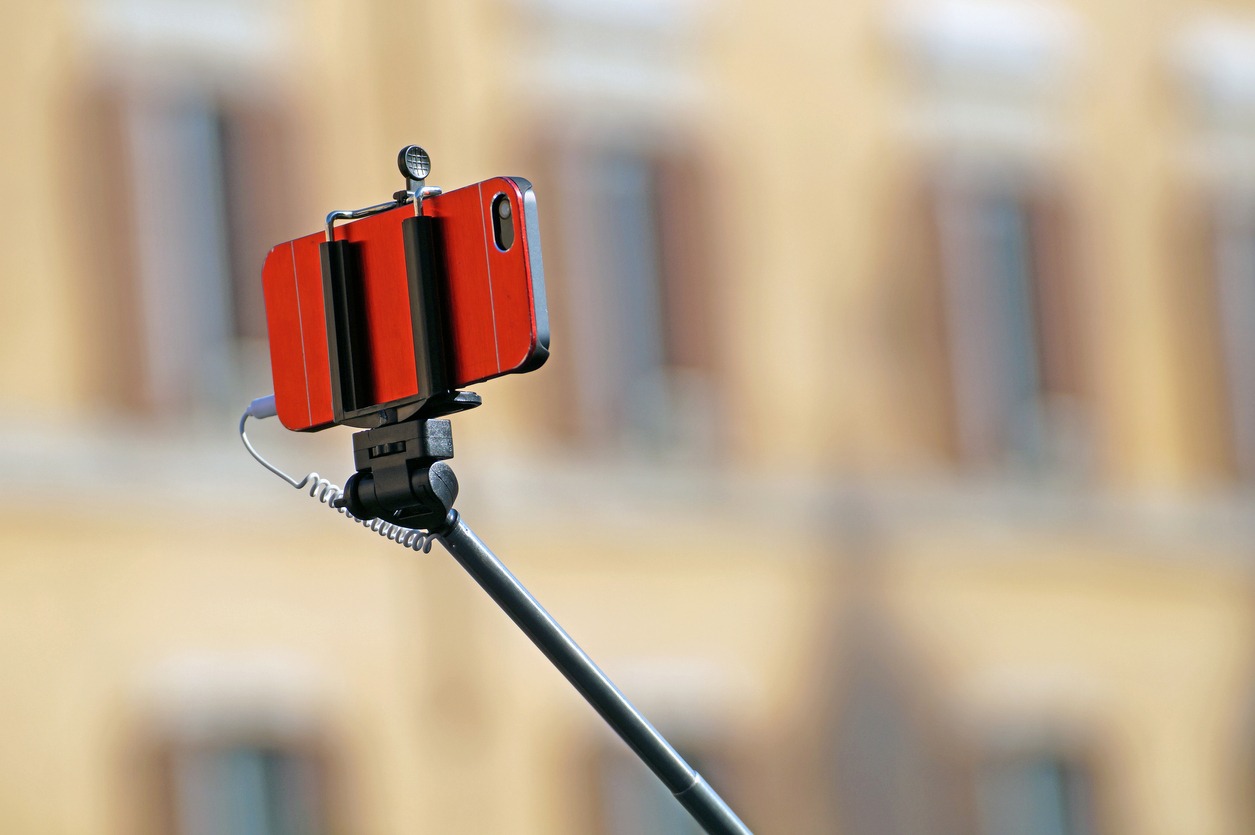 A phone attached to a selfie stick. 