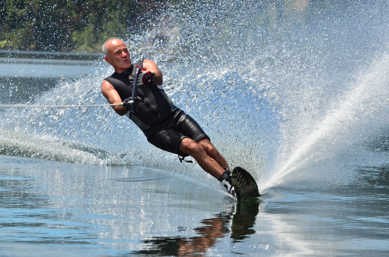 A water skier in his 60’s performing water skiing on a lake