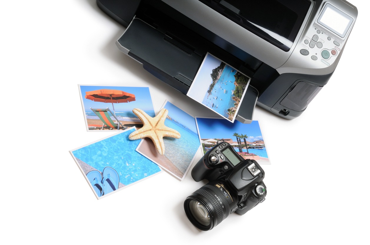An inkjet printer printing pictures of a sea with a camera next to it