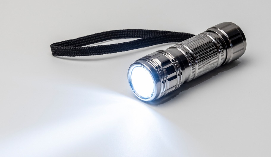 Black pocket LED flashlight on a white surface