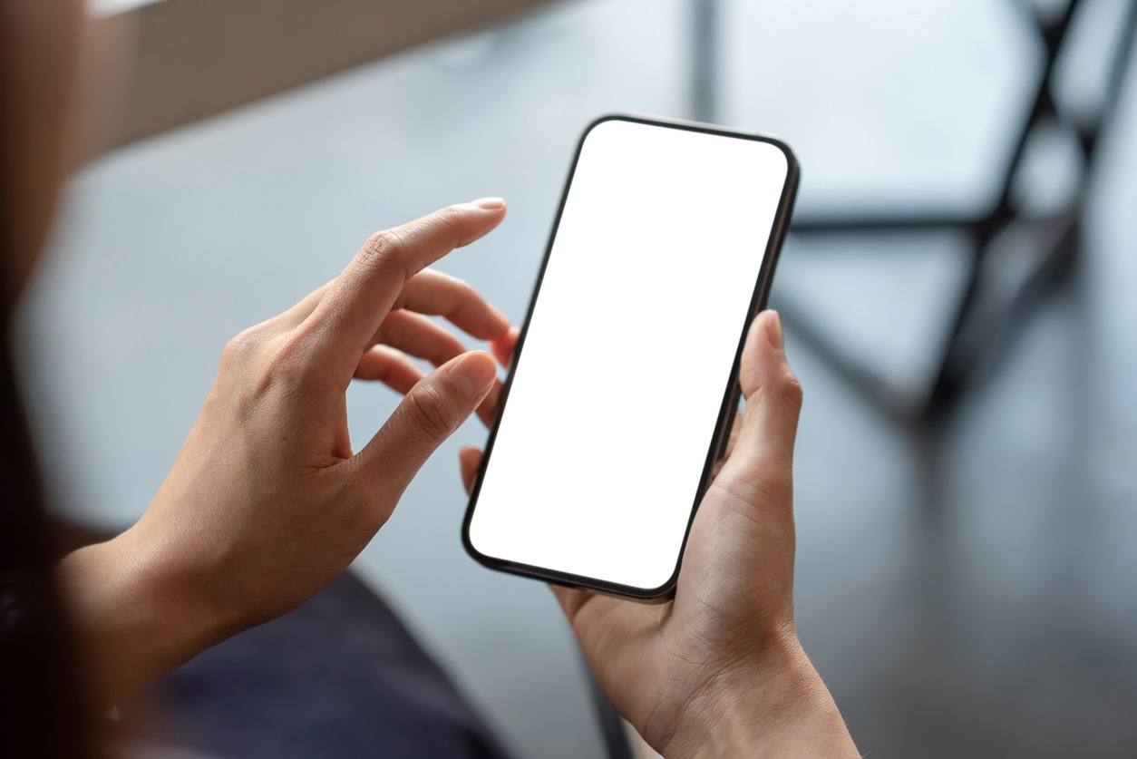 Close-up of a businessman hand holding a smartphone white screen is blank the background is blurred. Mockup