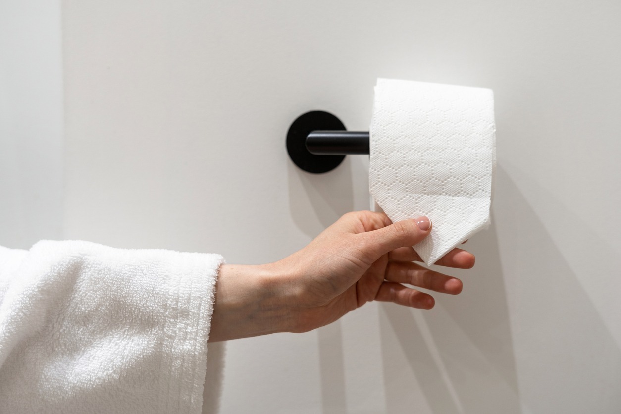 Cropped view of woman’s hand taking a piece of toilet paper with a folded corner. A woman holds a roll of soft hygienic tissue. Hygienic concepts in the hotel, home, and public restrooms
