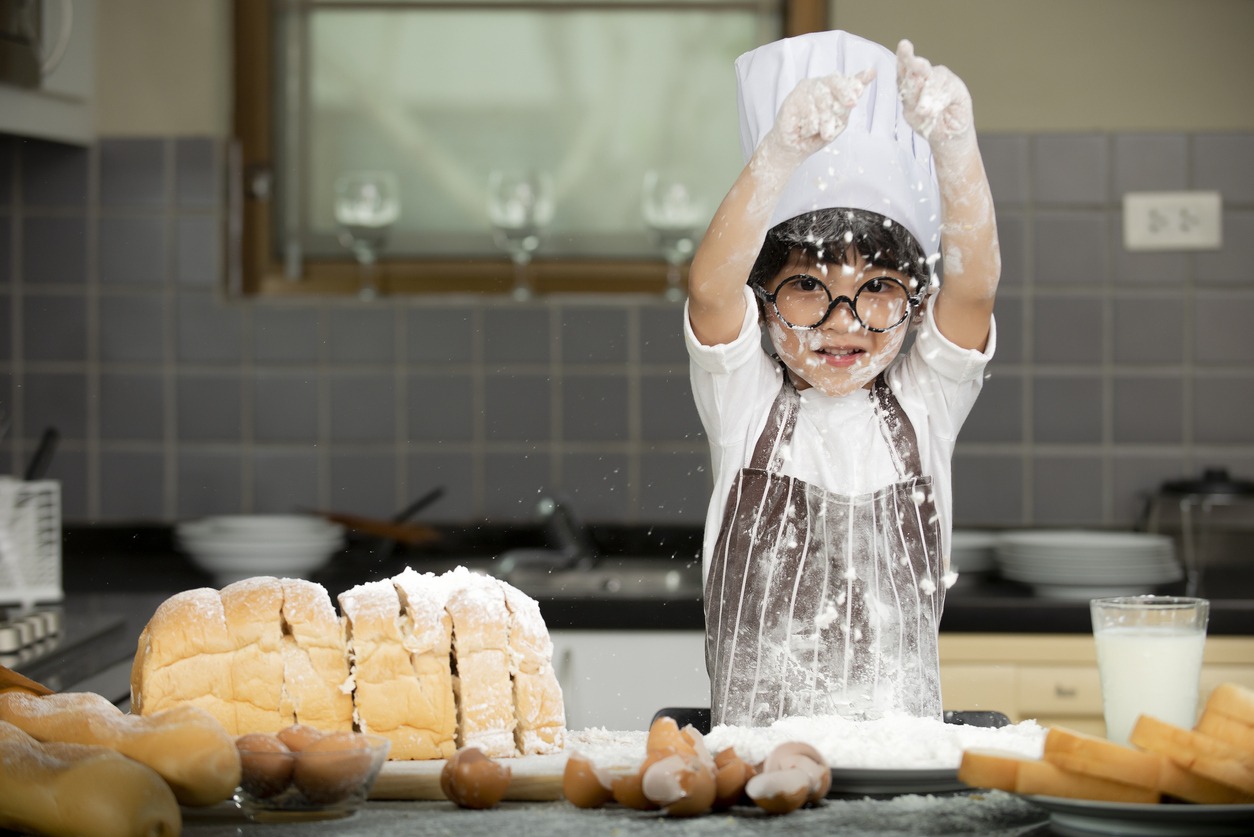 Happy cute Asian little boy in an apron preparing baking the dough in the kitchen room at home, Family lifestyle Concept