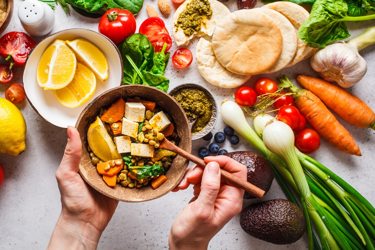Healthy vegetarian food background. Vegetables, hummus, pesto, and lentil curry with tofu