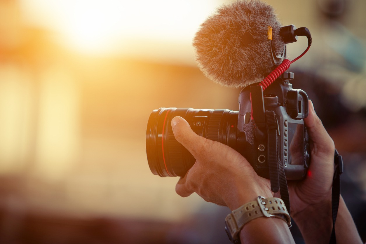 Man holding a camera with a fluffy microphone