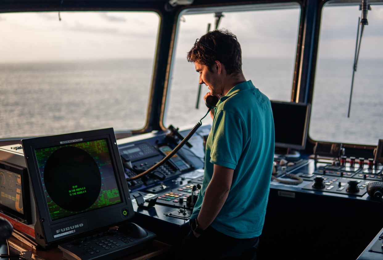 Marine navigational officer is reporting by VHF radio during navigation watch. Bridge GMDSS watch