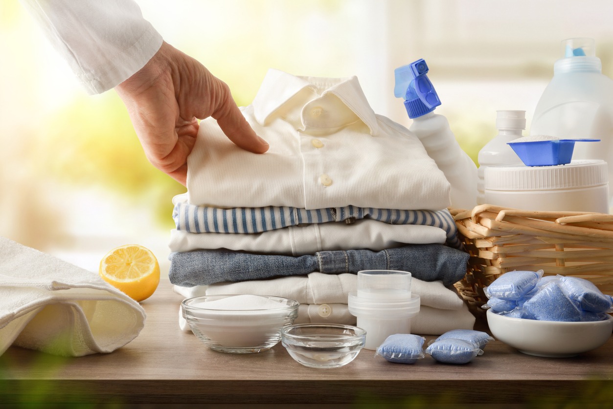 Products and person showing freshly washed clothes in a room with a window in the background. Front view. Horizontal composition