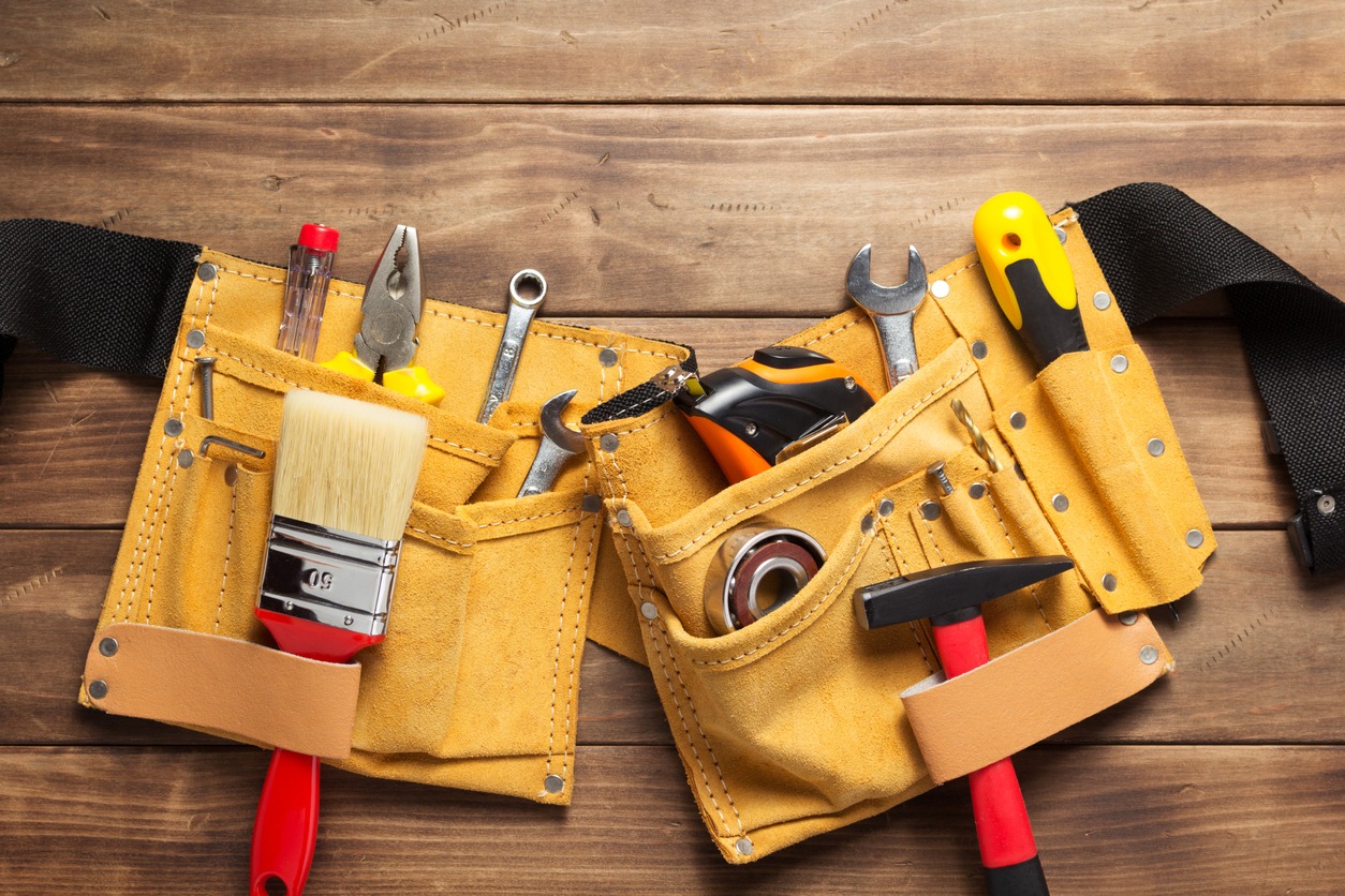 Tools and instruments in a yellow tool belt bag on a wooden background