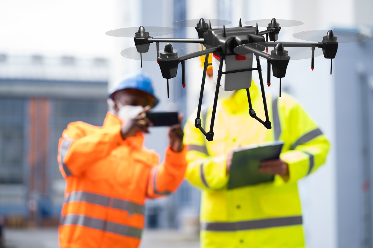 Two industrial workers use a drone at a site.