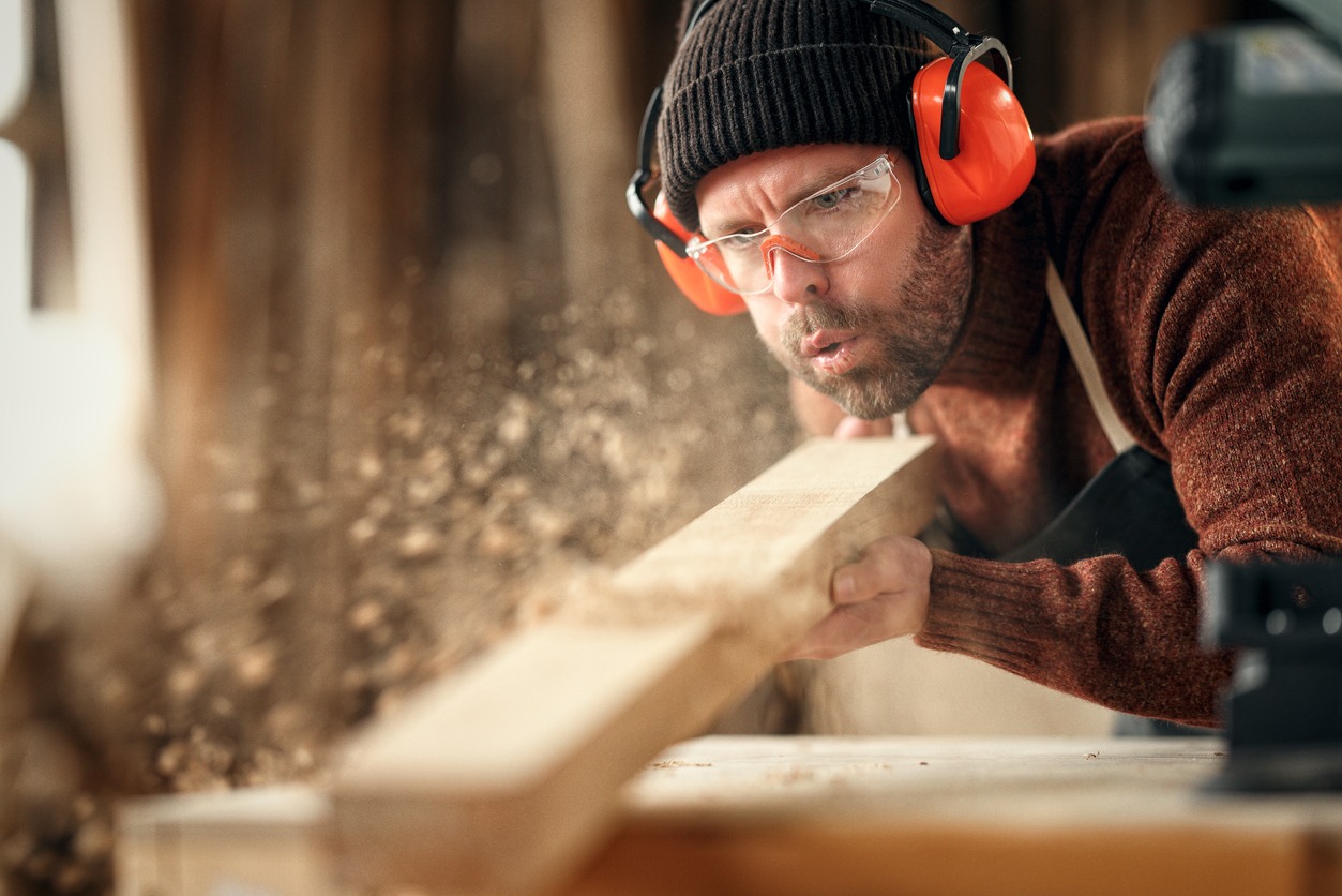 Woodworker blowing sawdust from his workpiece