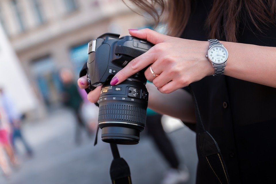 a-woman-holding-a-DSLR-camera-in-an-outdoor-setting