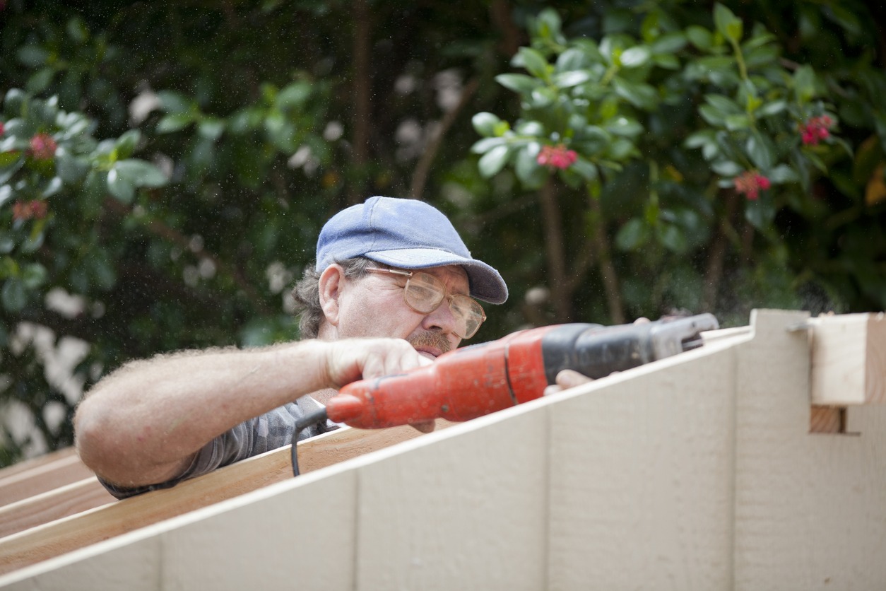 construction worker uses a reciprocating saw to finish the siding 