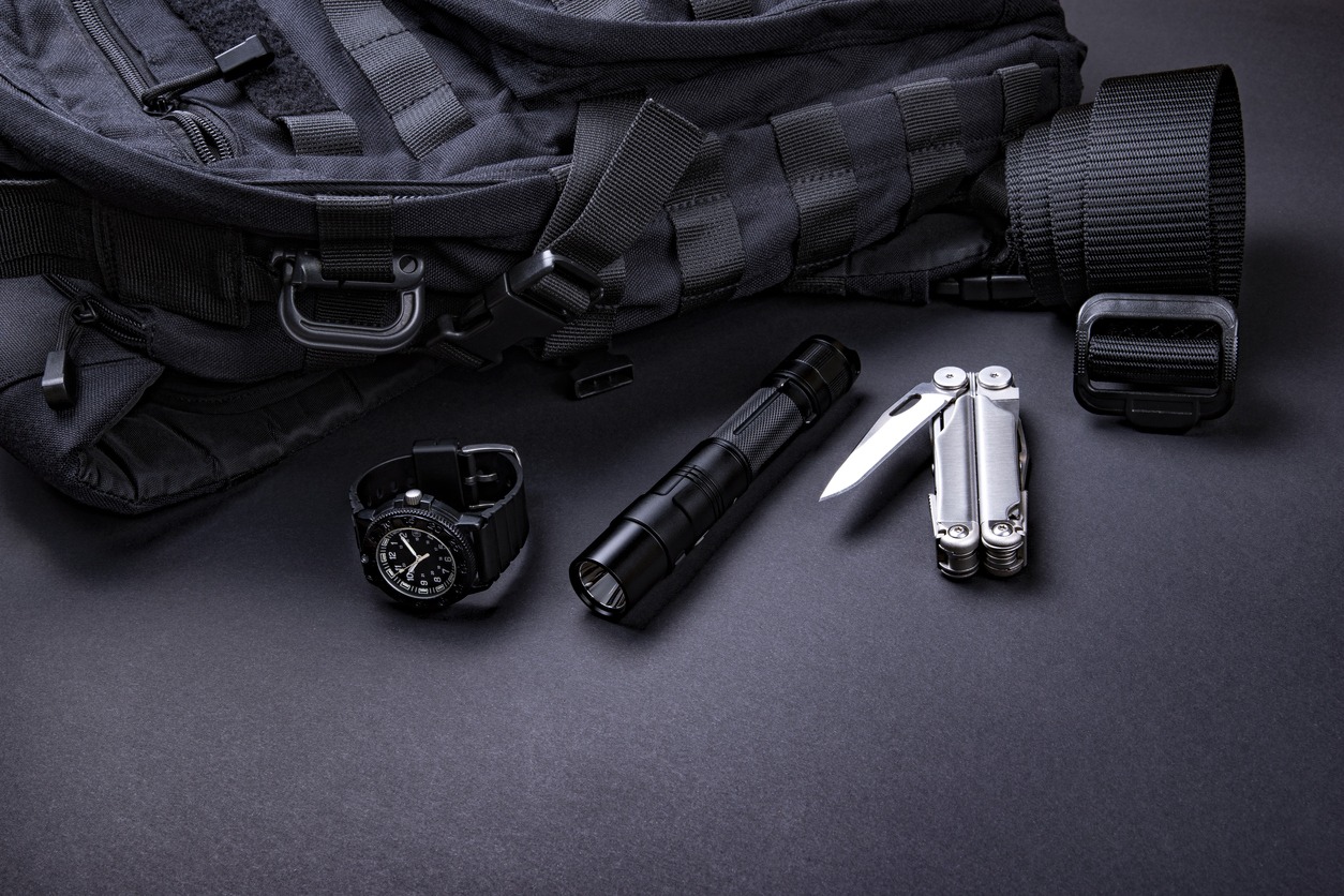 everyday carry (EDC) items for men in black color - backpack, tactical belt, flashlight, watch, and silver multi-tool. Survival set. Minimal concept