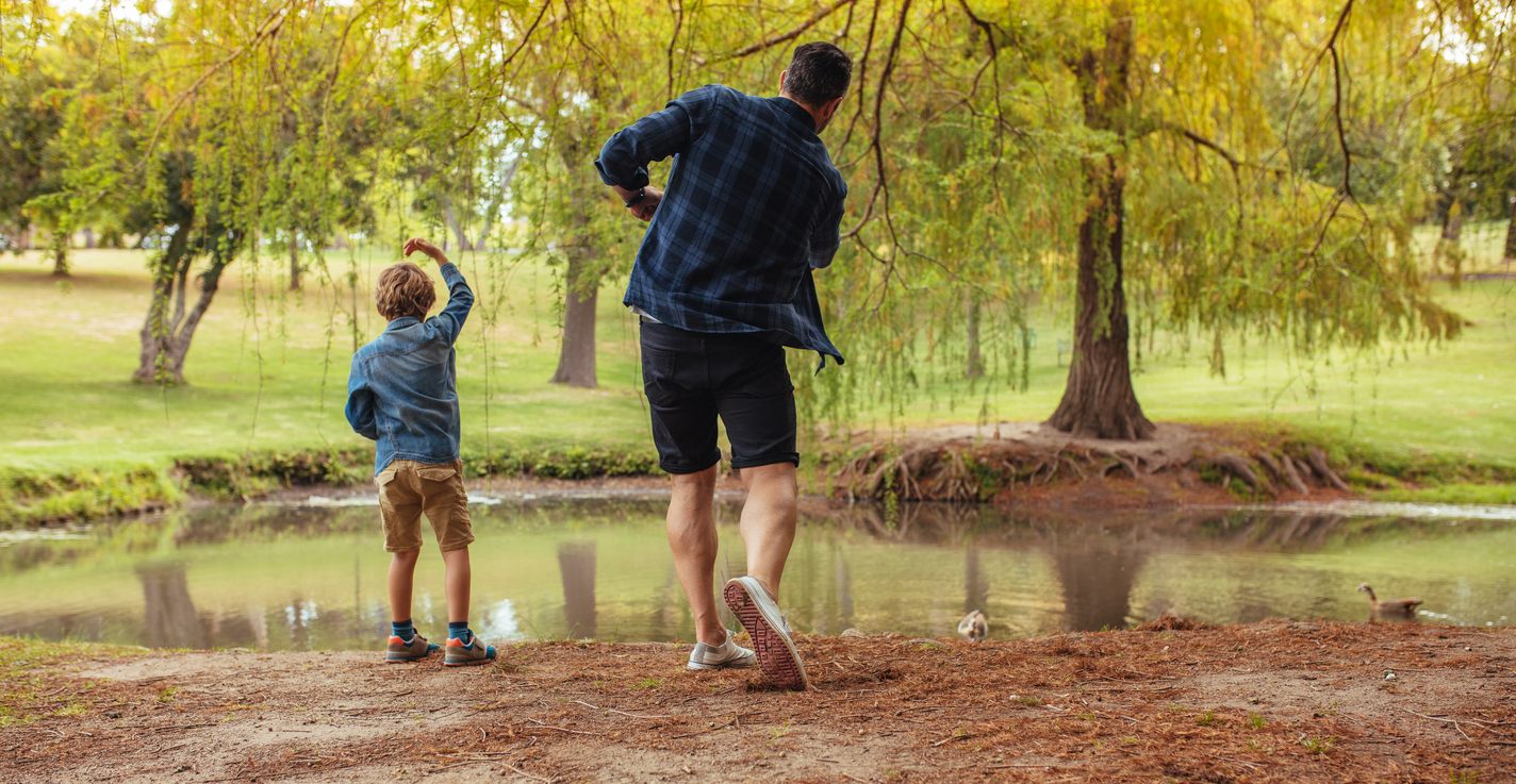 father and son throwing rocks in a pond