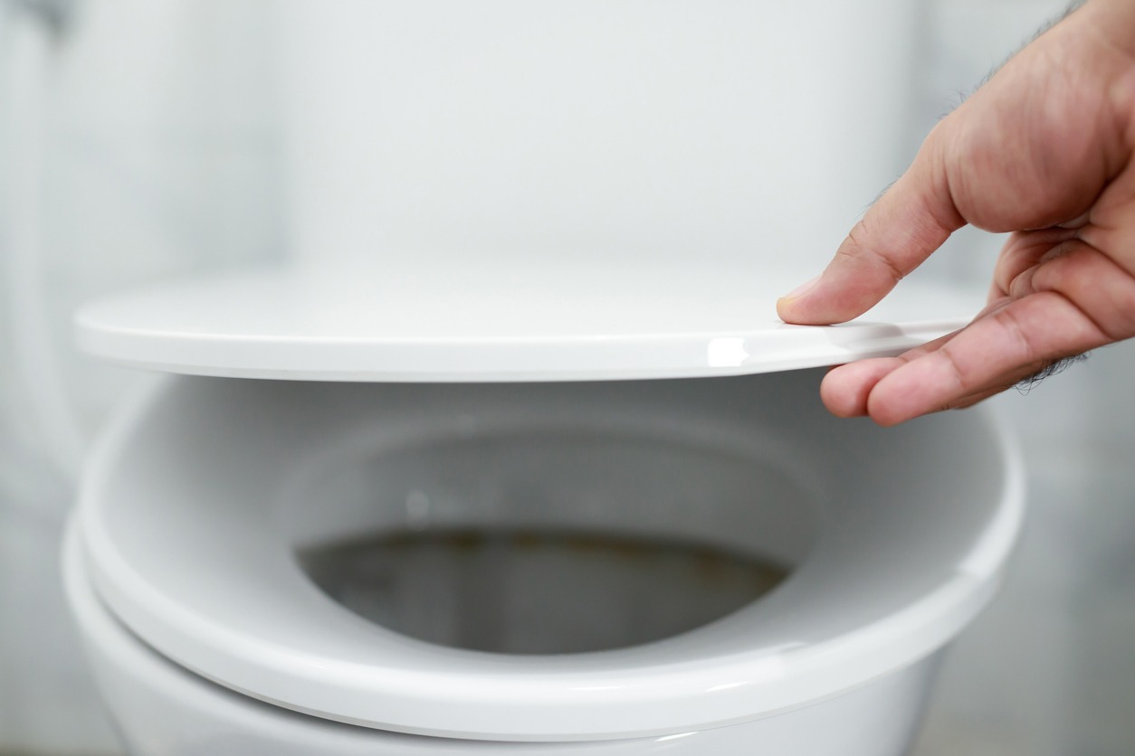 man's hand opening the toilet lid