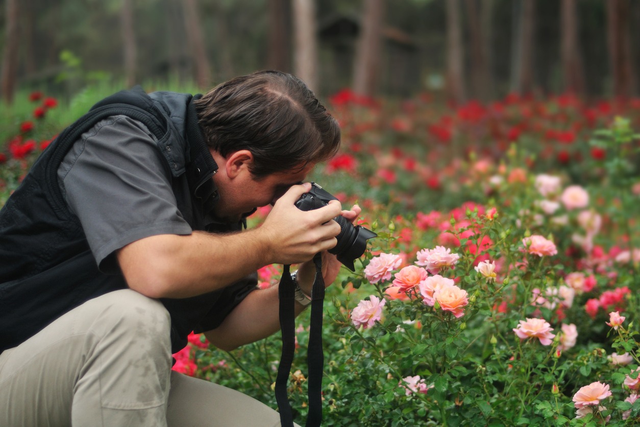 young person photographing flowers with a camera