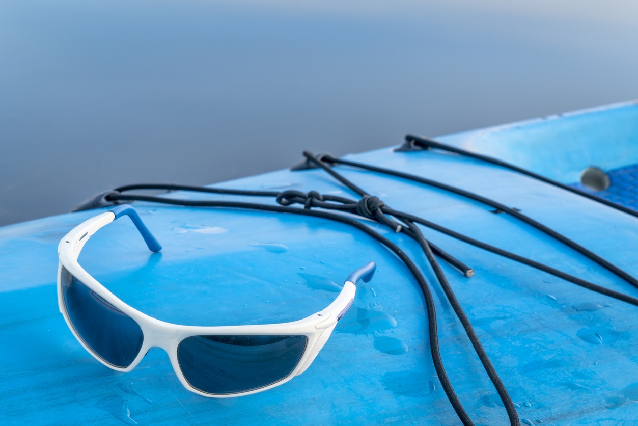 A pair of sports sunglasses on a standup paddleboard