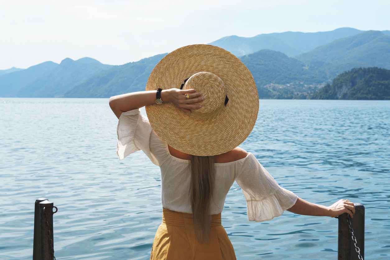 A woman wearing a wide-brimmed hat by a lake