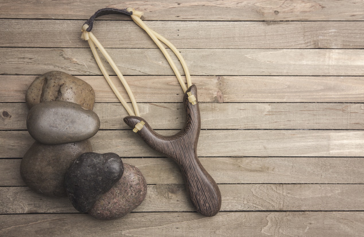 A wooden slingshot with rocks on a table. 