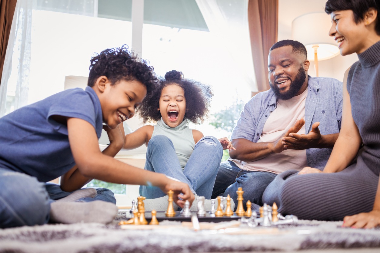 Children playing chess with mom and dad at home