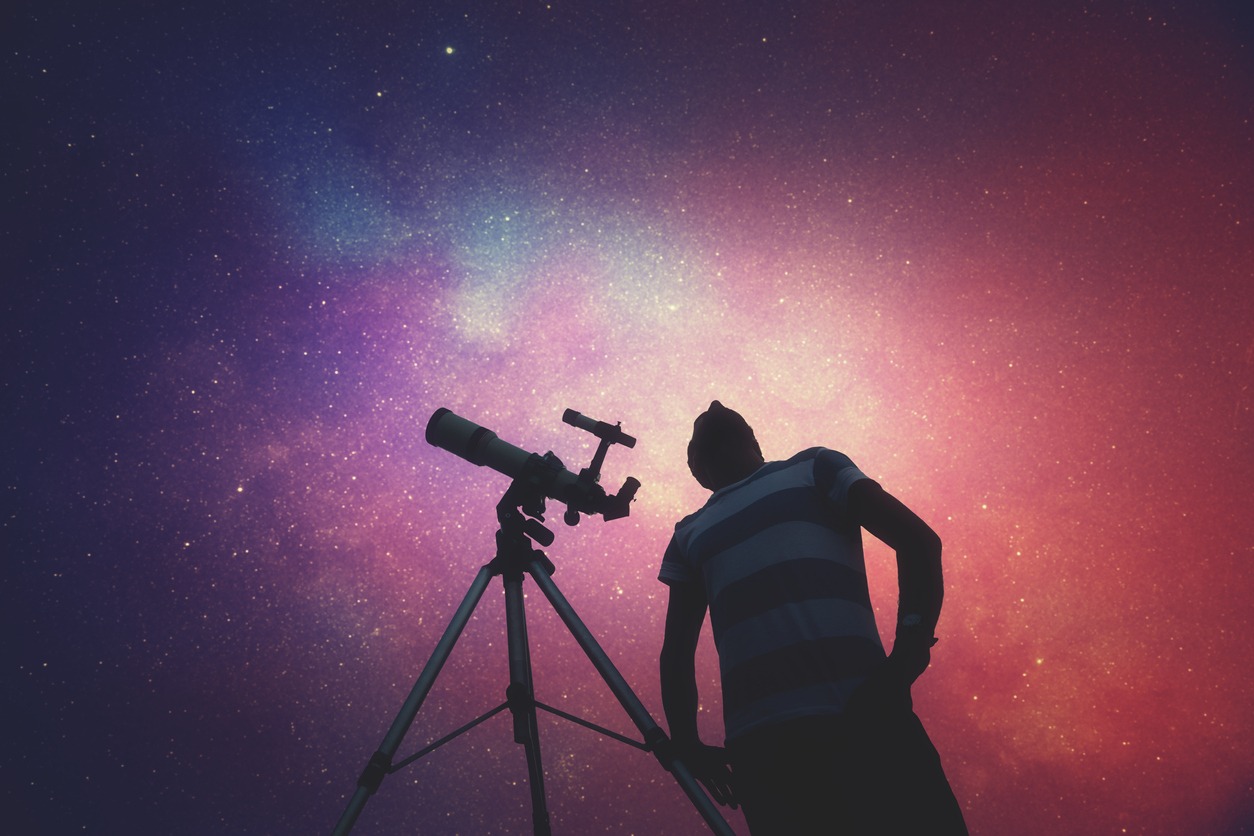 Man looking at the stars with telescope behind him
