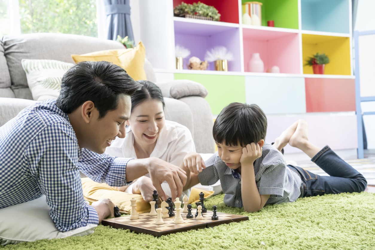 Time with loved one concept, Happy Asian family playing chess game in the living room together
