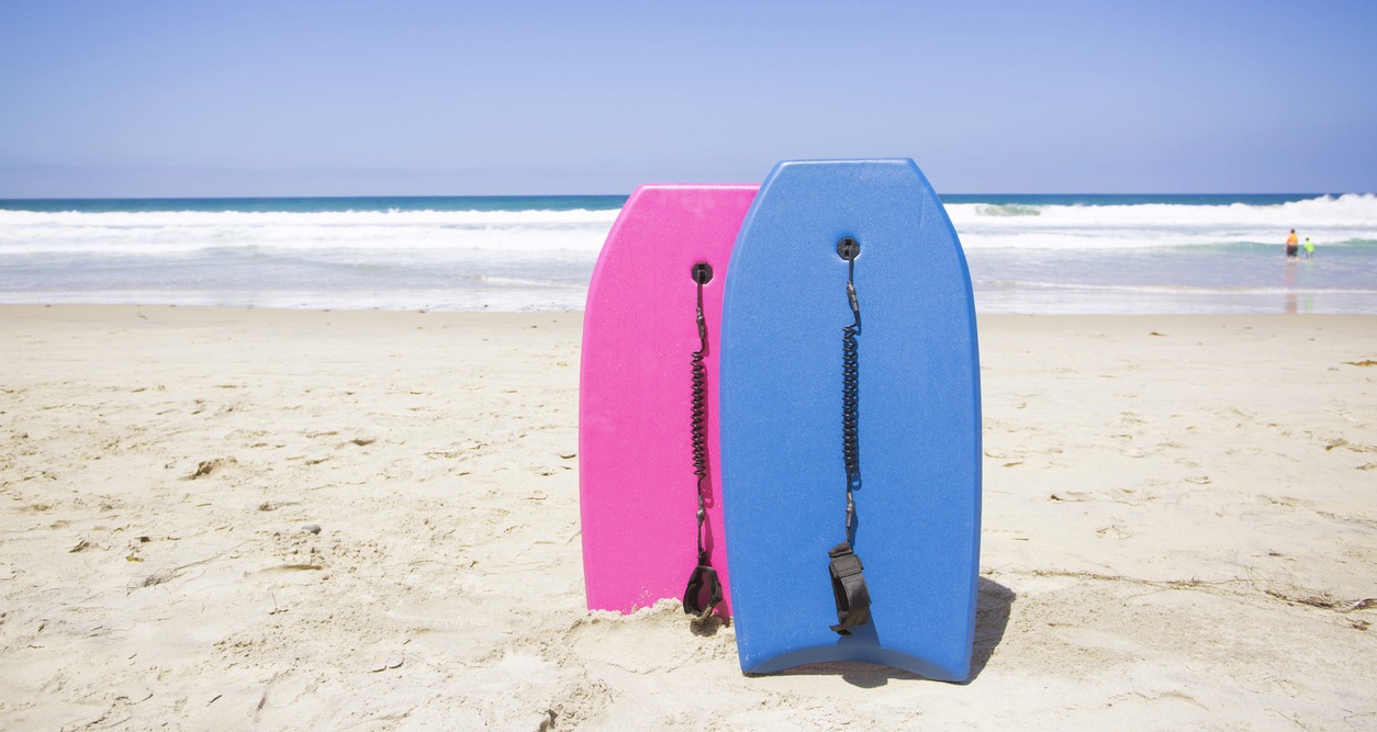 Two colorful boogie boards resting on a pristine beach.