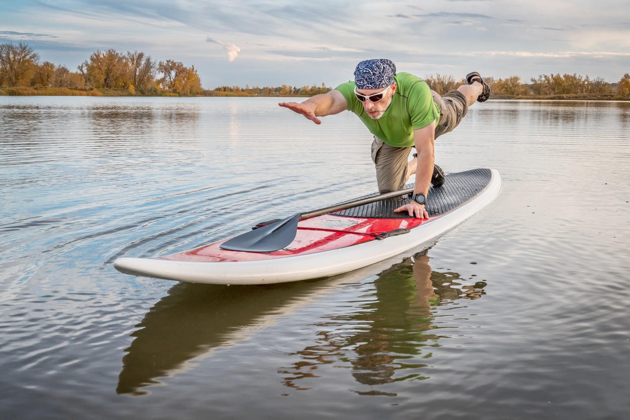 a man balancing on a stand-up paddleboard