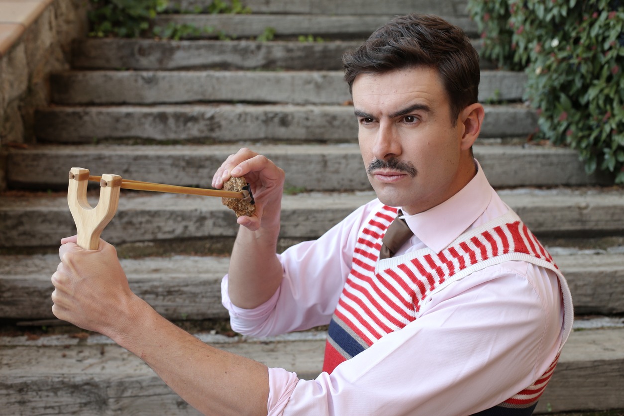 Elegant man with a mustache holding vintage slingshot