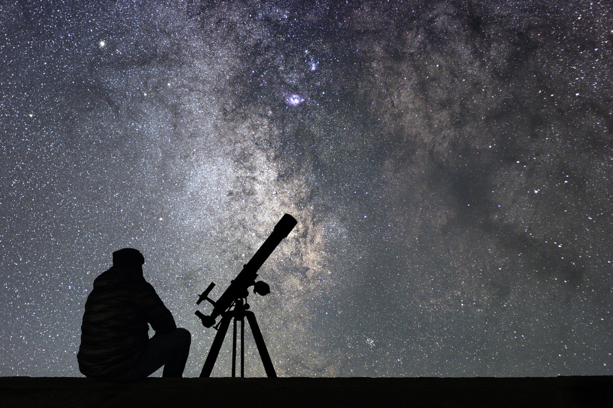 man with astronomy telescope looking at the stars