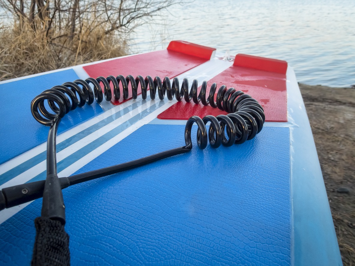 coil safety leash on a deck of standup paddleboard - safety equipment