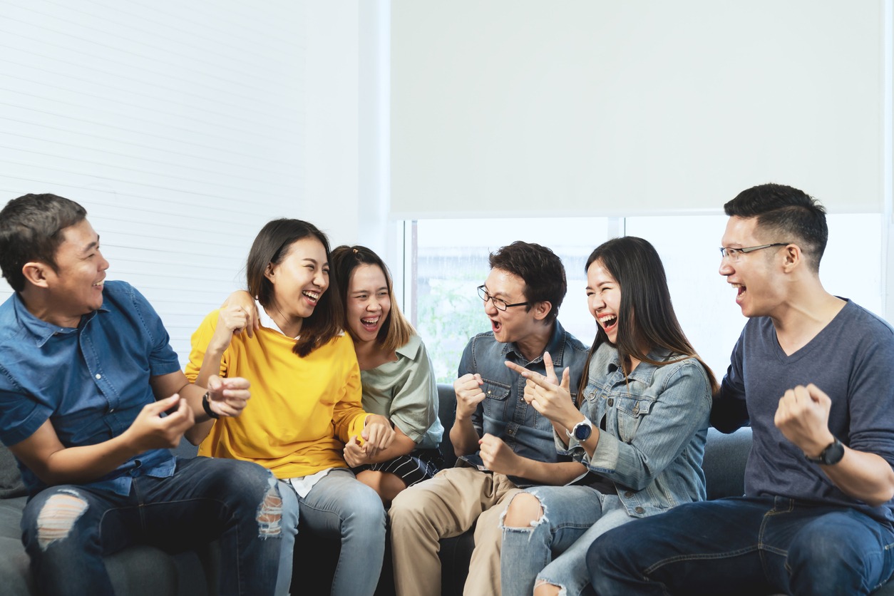 Young Attractive asian group of friends talking and laughing with happy in gathering meeting sitting at home feeling cheerful and enjoy game in leisure time together