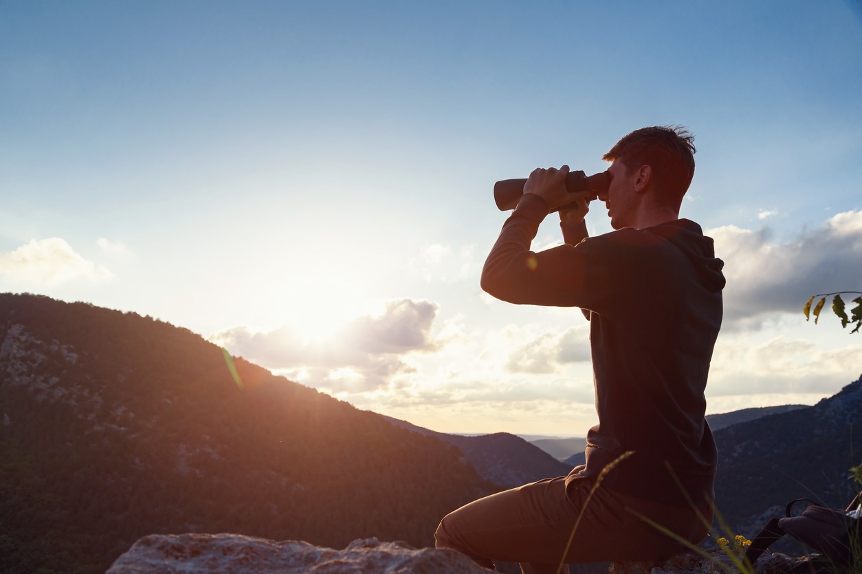 A young man looking through his binoculars