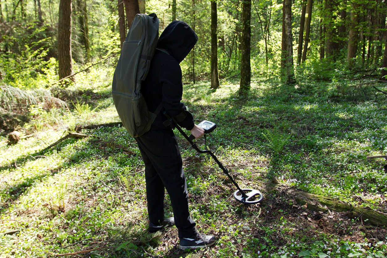 a man with a metal detector in the woods