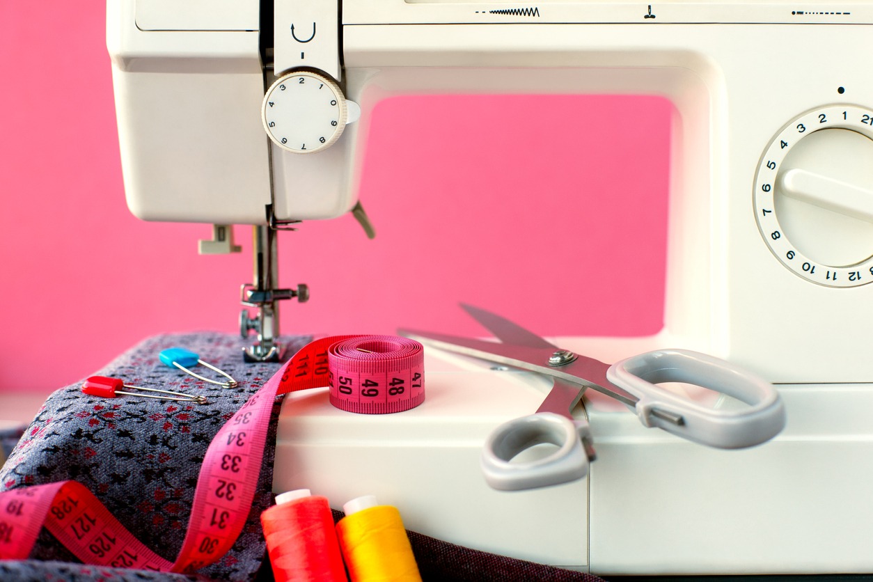 Sewing machine and cloth on a pink background.