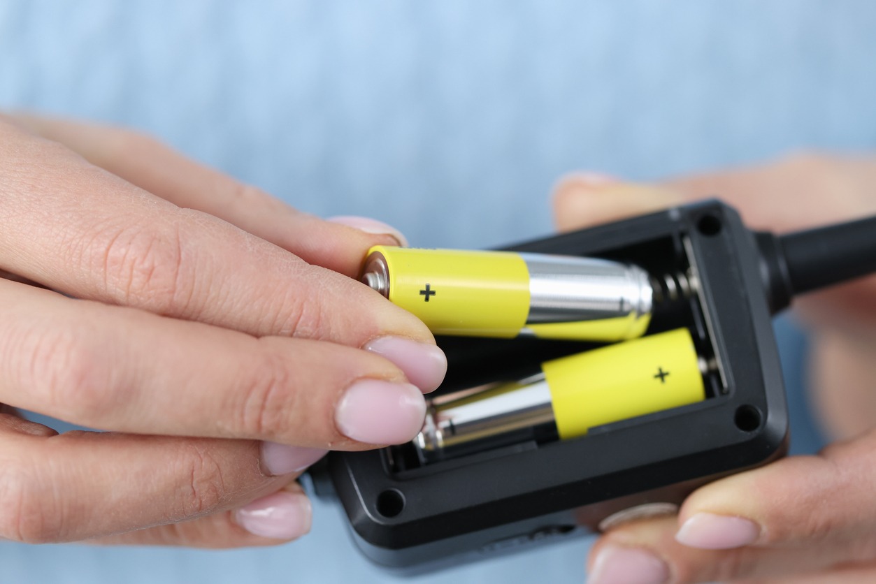 Female hands inserting batteries into remote closeup