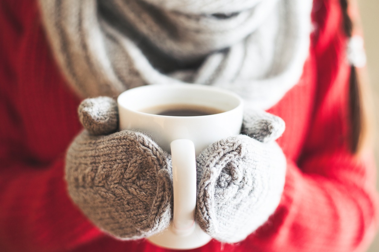 Woman hands in gloves holding a mug