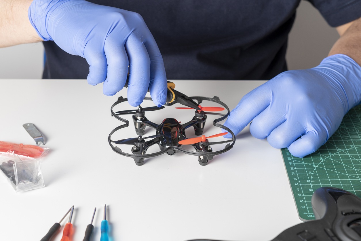 Man working on a drone with gloved hands