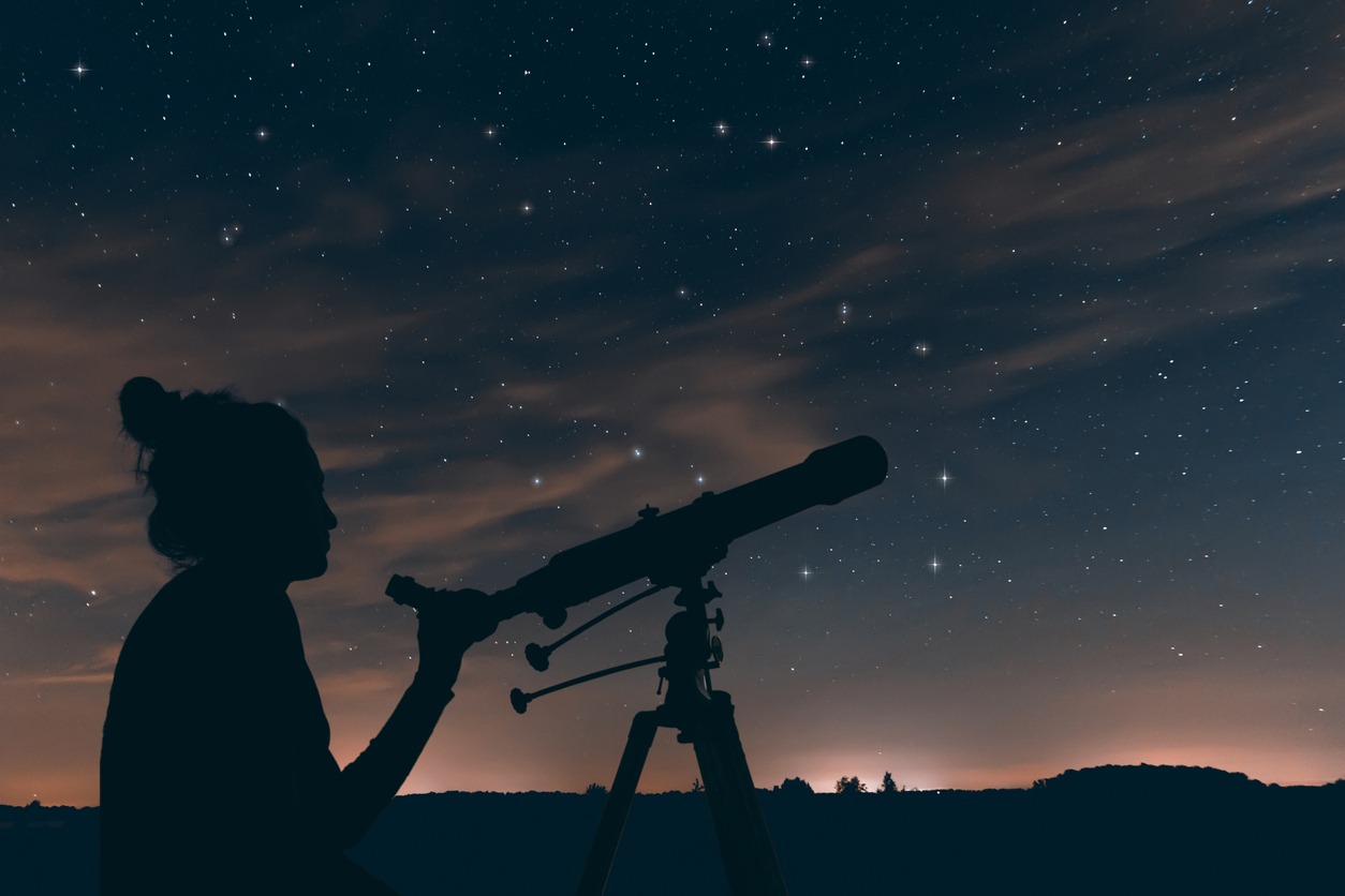 Woman observing the night sky with a telescope