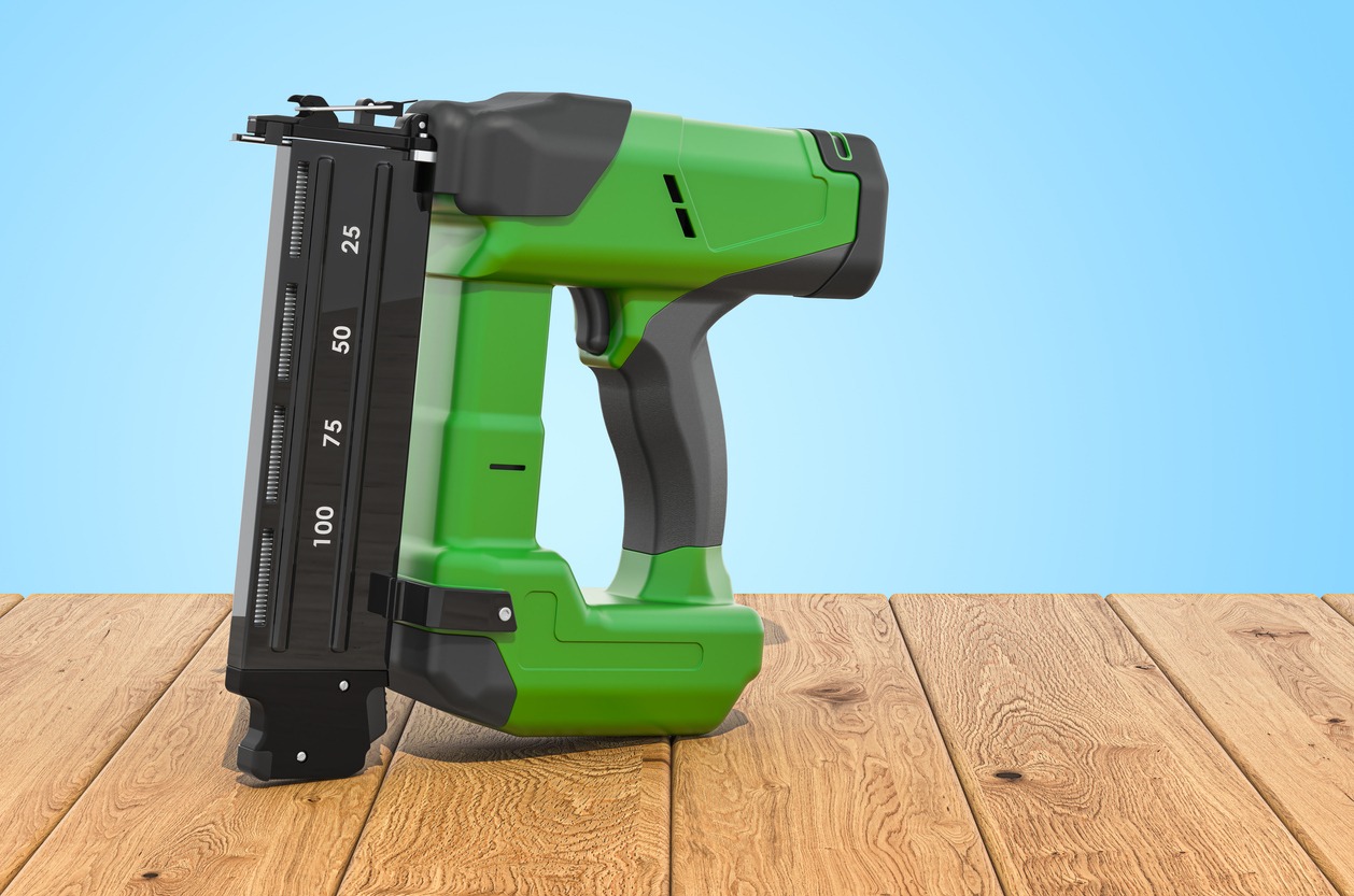 a cordless nail gun placed O on wooden planks