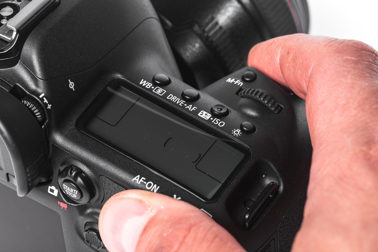 person holding a DSLR with various settings like ISO