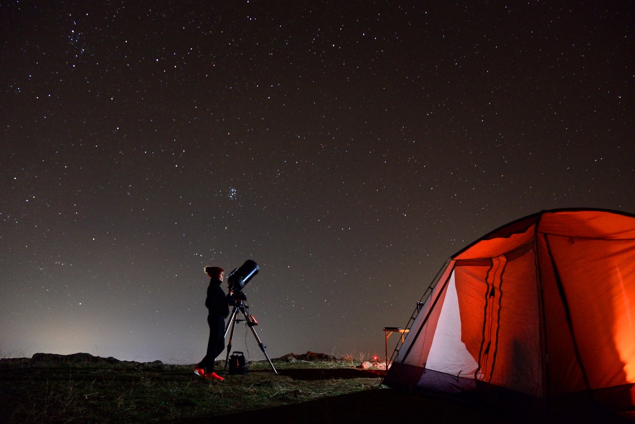 traveler observing the stars with her telescope
