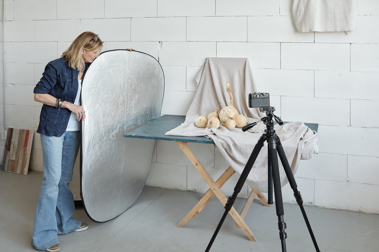 woman adjusting a reflector panel for desired lighting effect